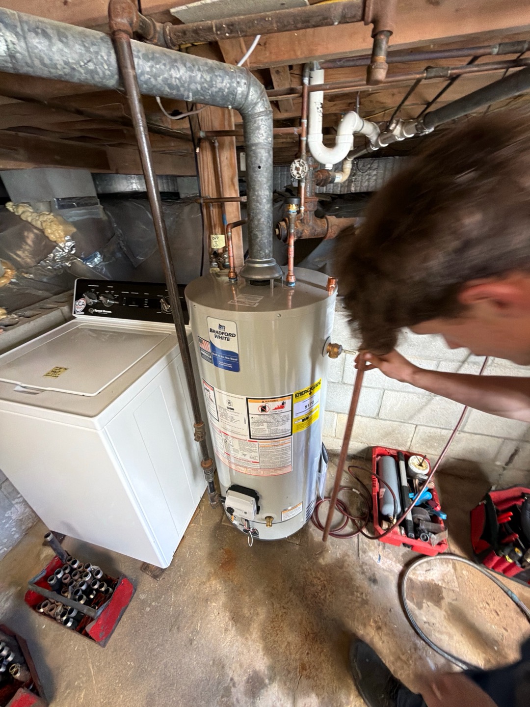 Technician working beside a Bradford White 40-gallon natural gas replacement water heater in a Dennis, MA basement